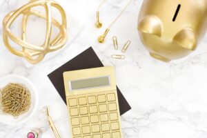 Desk covered with lots of gold items, including a gold calculator and a gold piggy bank