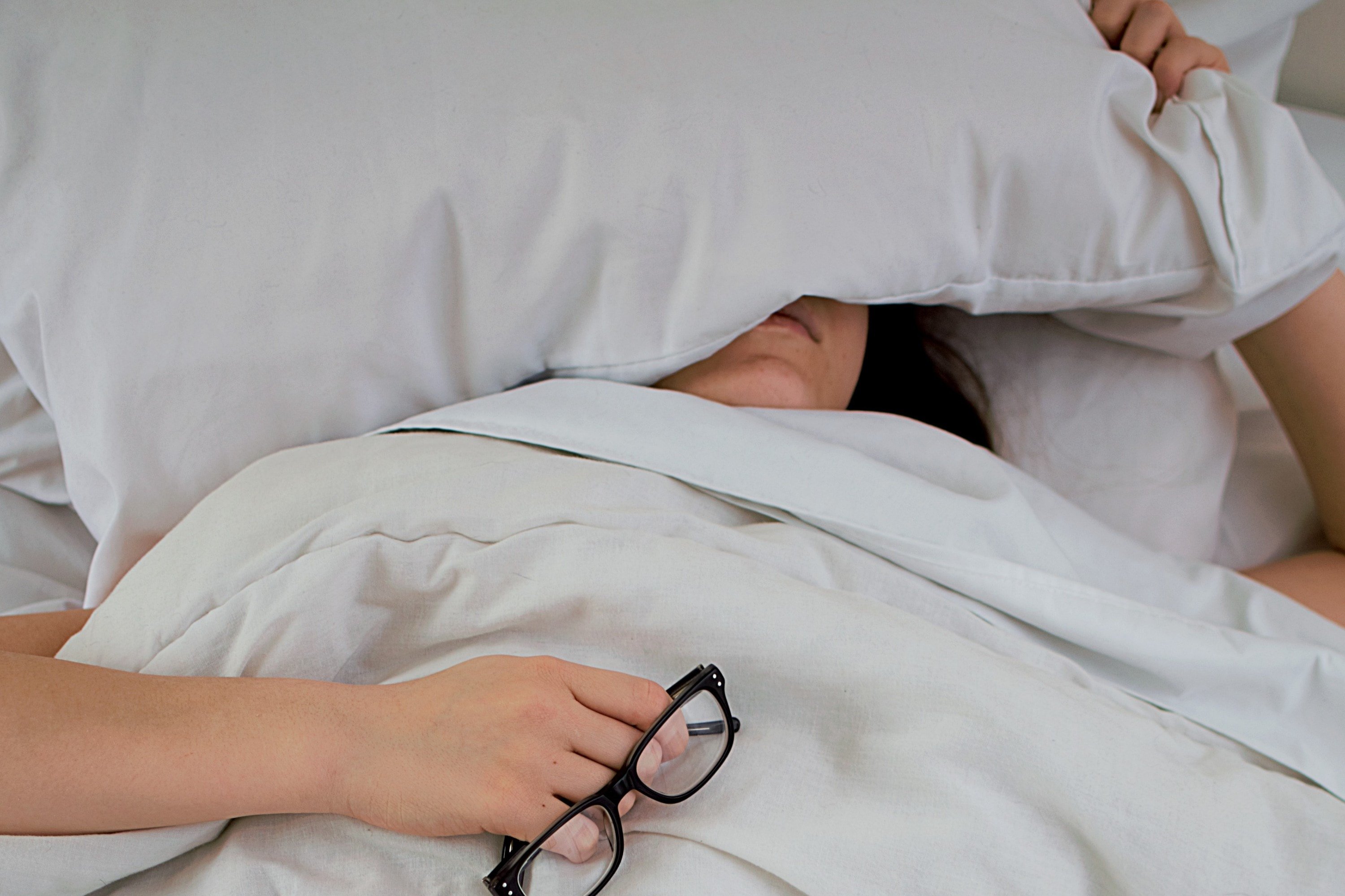 Woman asleep in bed, her face is under the pillow